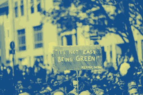 Une photo de manifestation. Une pancarte indique "it's not easy beeing green !"