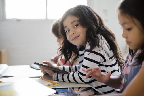 Girls sit a table working on touchscreen tablets